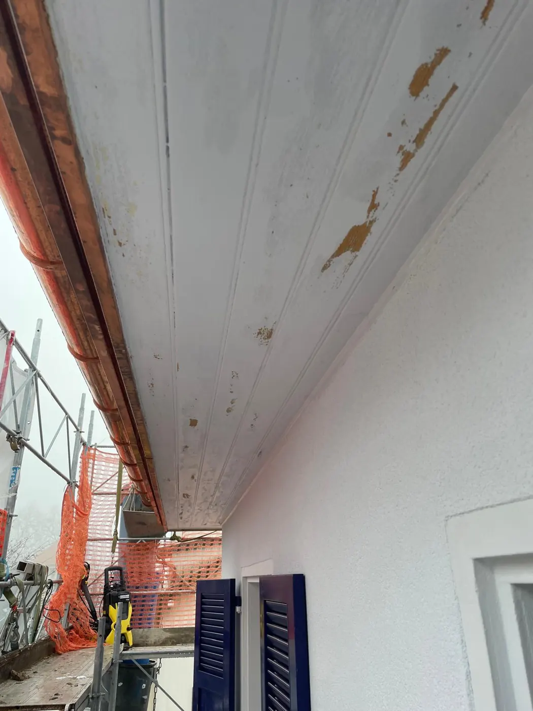 Sous-face d’avant-toit avec la peinture écaillée, avant les travaux